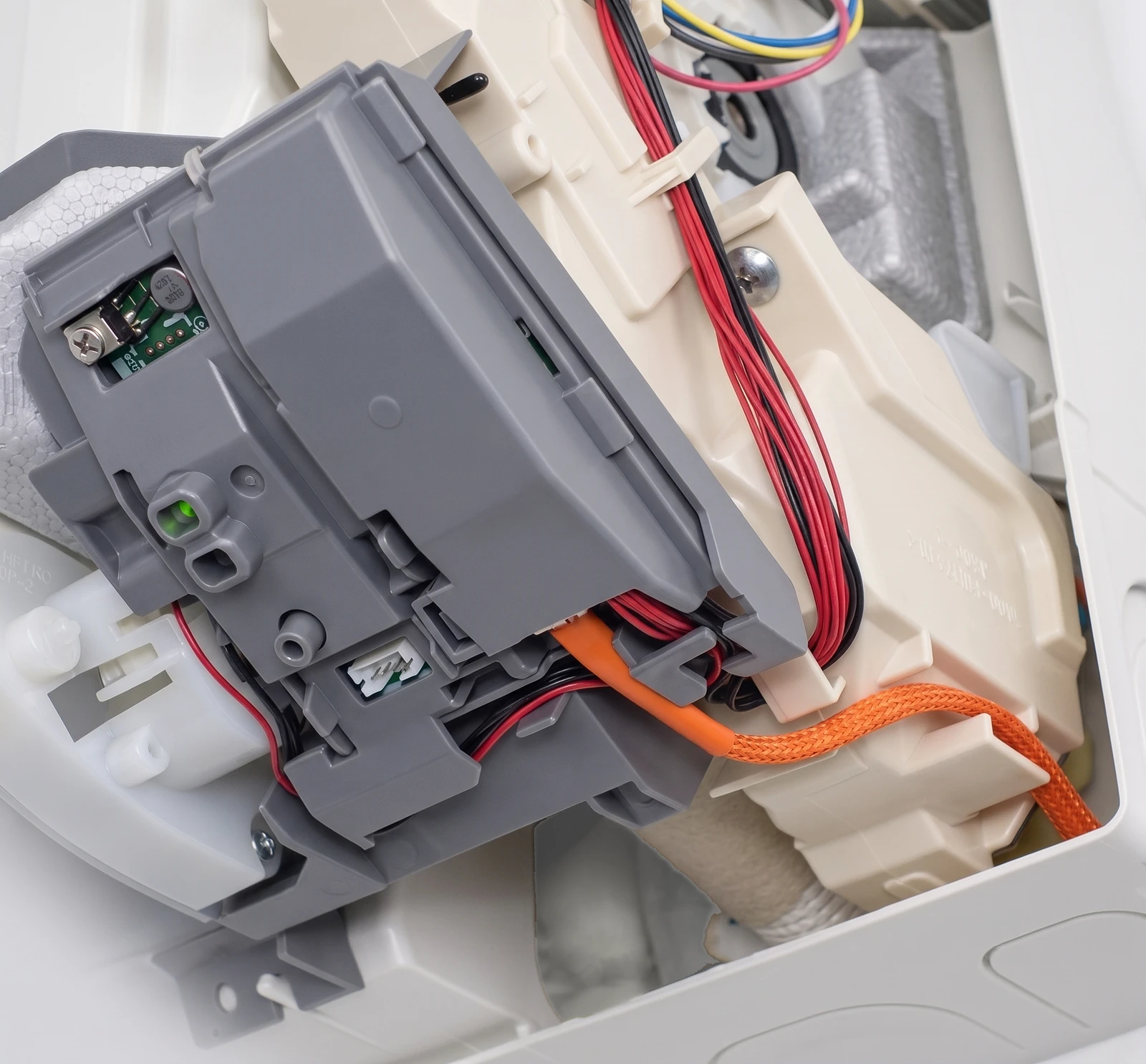The orange CN105-to-Grove cable routed into the electrical box of a Mitsubishi wall unit, running under a retaining clip and beneath the control-board cover