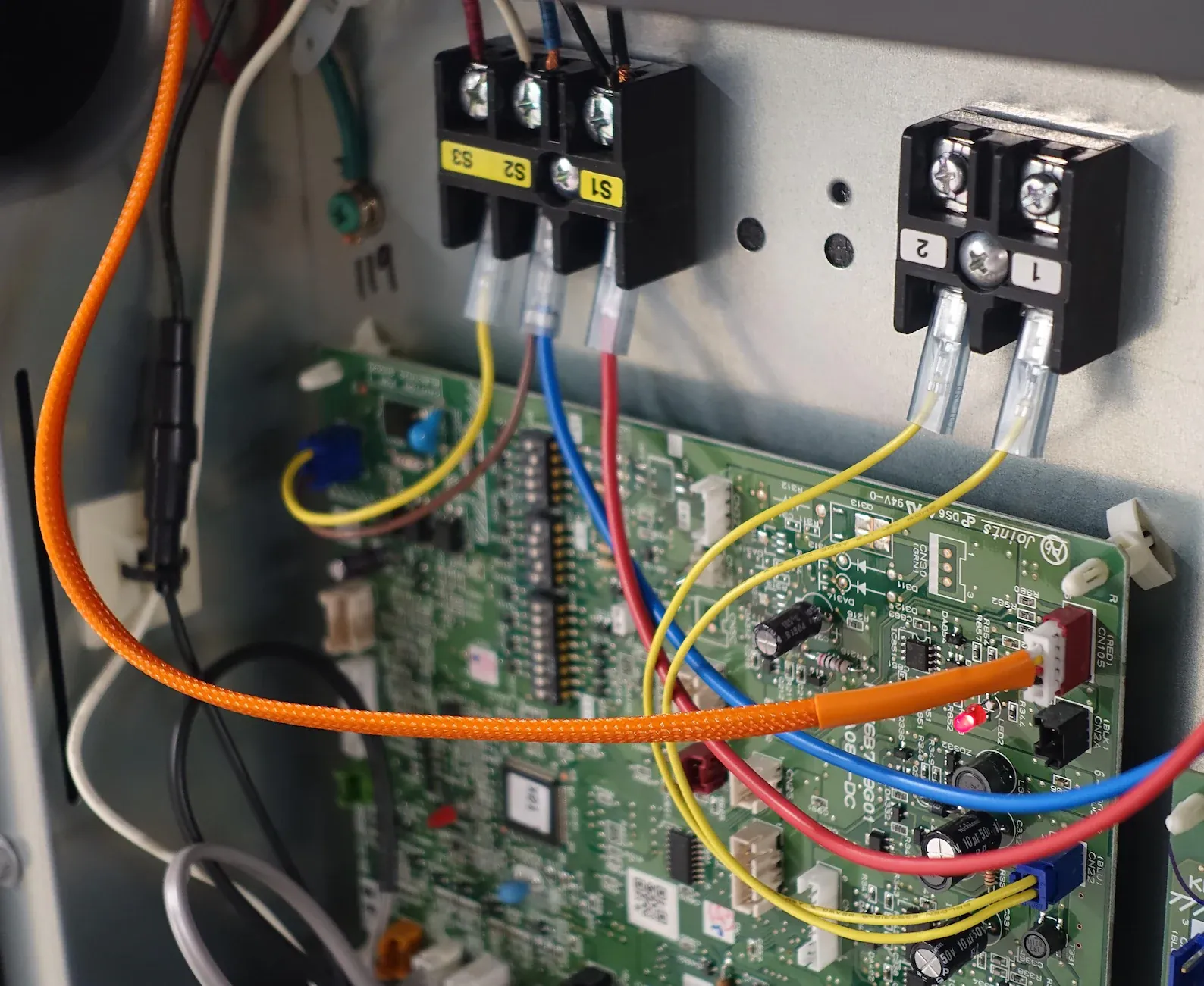 The CN105 port on a Mitsubishi indoor unit's control board, with an orange cable connected to it